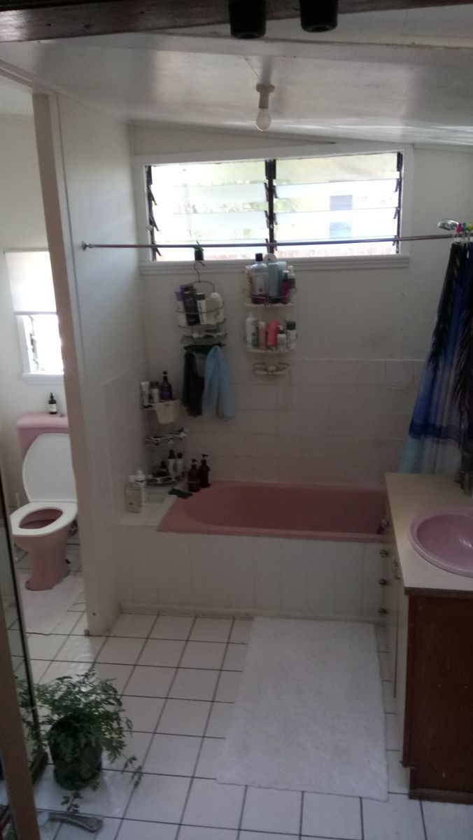 A Bathroom With a Pink Bathtub , Sink , Toilet and Window — Omni Builders In Bungalow, QLD