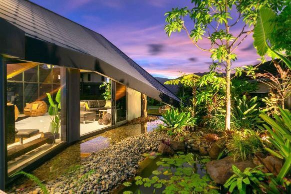 A House With A Pond In Front Of It And A Lot Of Windows — Omni Builders In Bungalow, QLD