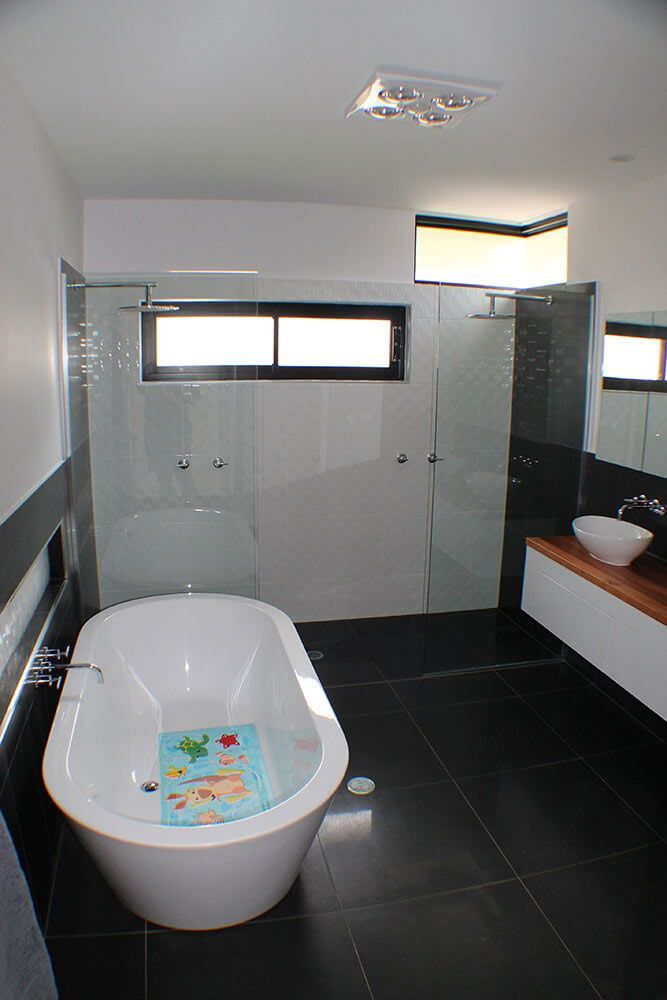 A Bathroom With A Bathtub, Sink, And Shower — Omni Builders In Bungalow, QLD