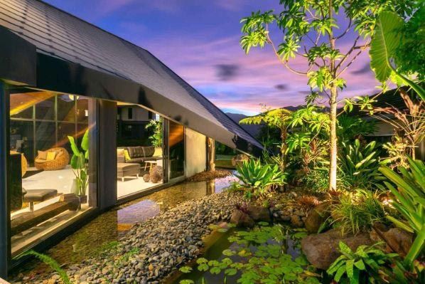 A Large House With A Pond In Front Of It — Omni Builders In Bungalow, QLD
