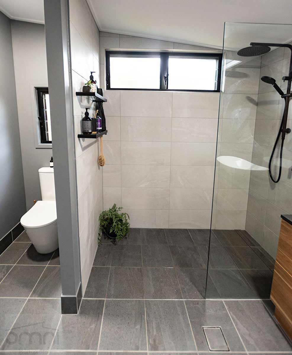 A Bathroom With A Walk In Shower And A Toilet — Omni Builders In Bungalow, QLD