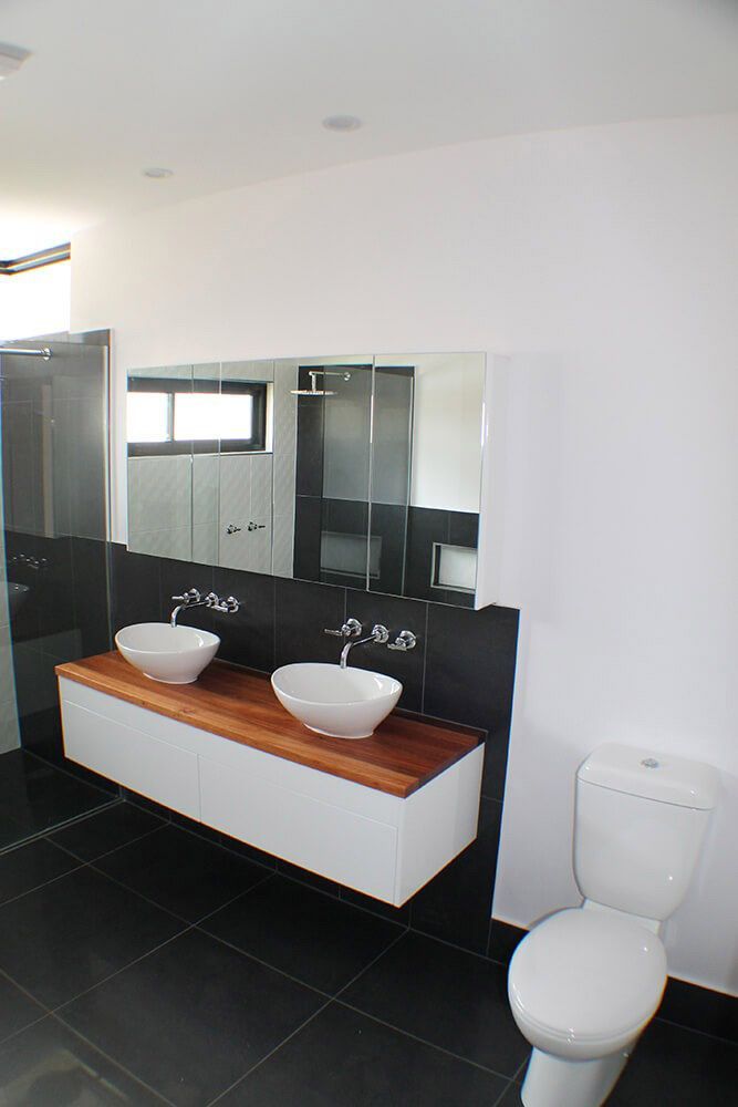 A Bathroom With Two Sinks And A Toilet — Omni Builders In Bungalow, QLD