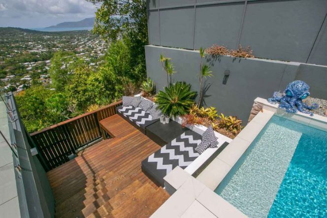A Swimming Pool With A Wooden Deck And Stairs Leading To It — Omni Builders In Bungalow, QLD