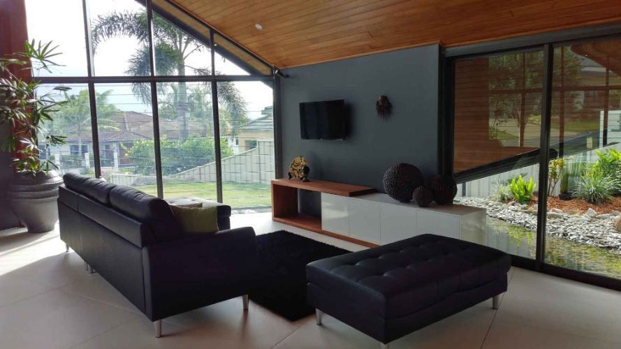 A Living Room With A Couch, Ottoma, And Television — Omni Builders In Bungalow, QLD