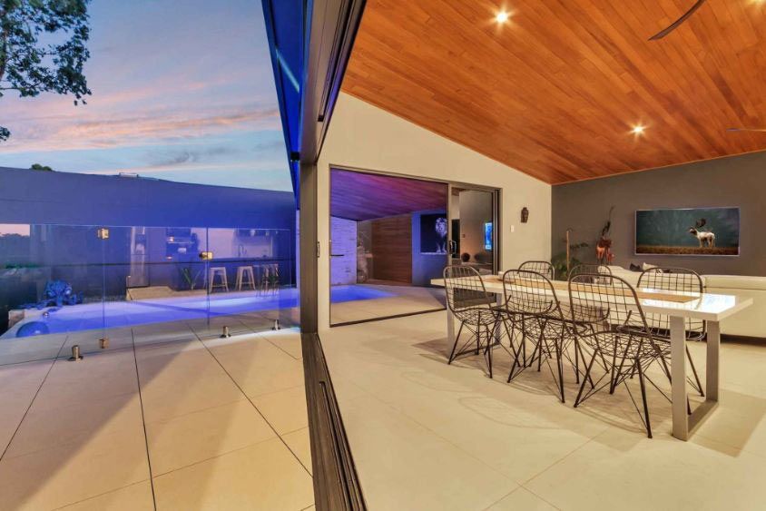 A Dining Room With A Table And Chairs And A Pool In The Background — Omni Builders In Bungalow, QLD