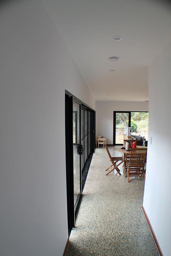 A Long Hallway In A House With A Table And Chairs — Omni Builders In Bungalow, QLD
