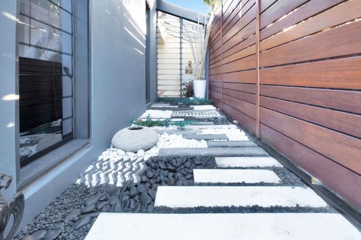 A Wooden Fence Surrounds a Narrow Walkway Between Two Buildings — Omni Builders In Bungalow, QLD