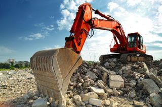 A red excavator is working on a pile of rocks.