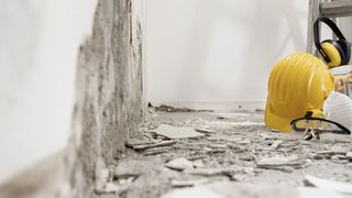 A yellow hard hat and ear muffs are on the floor of a construction site.