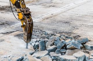 A bulldozer is breaking up concrete on a construction site.