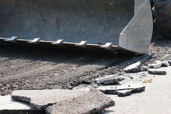 A bulldozer is breaking up concrete on the ground