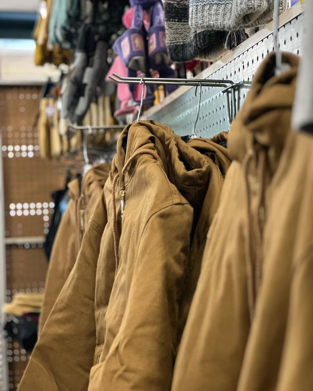 Brown work jackets hanging on a rack in a store.