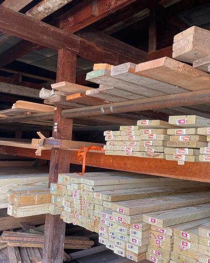Wood planks stacked on shelves in a lumberyard, different sizes and colors, organized storage.
