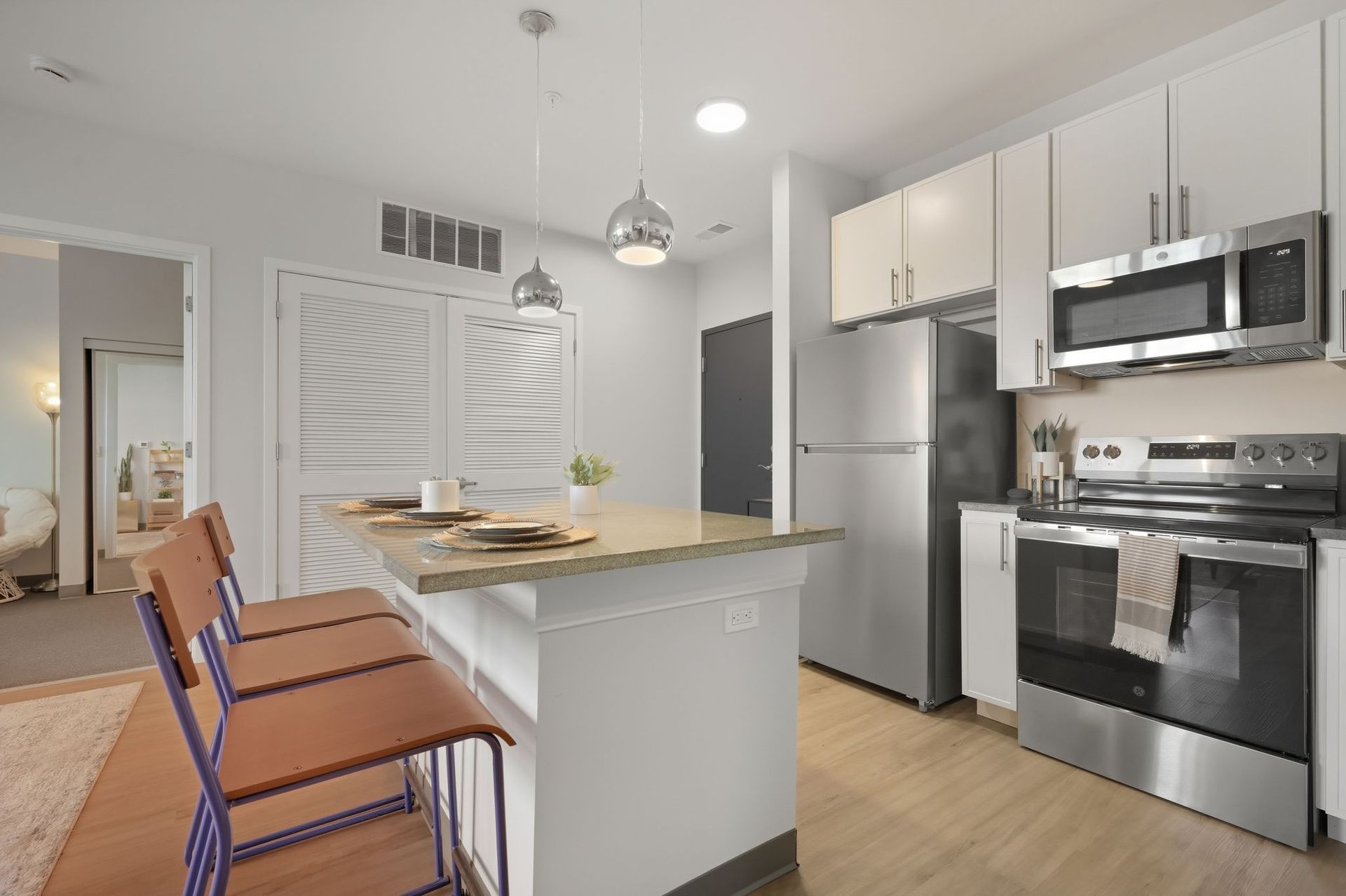 Modern kitchen with island, stainless steel appliances, and two bar stools.
