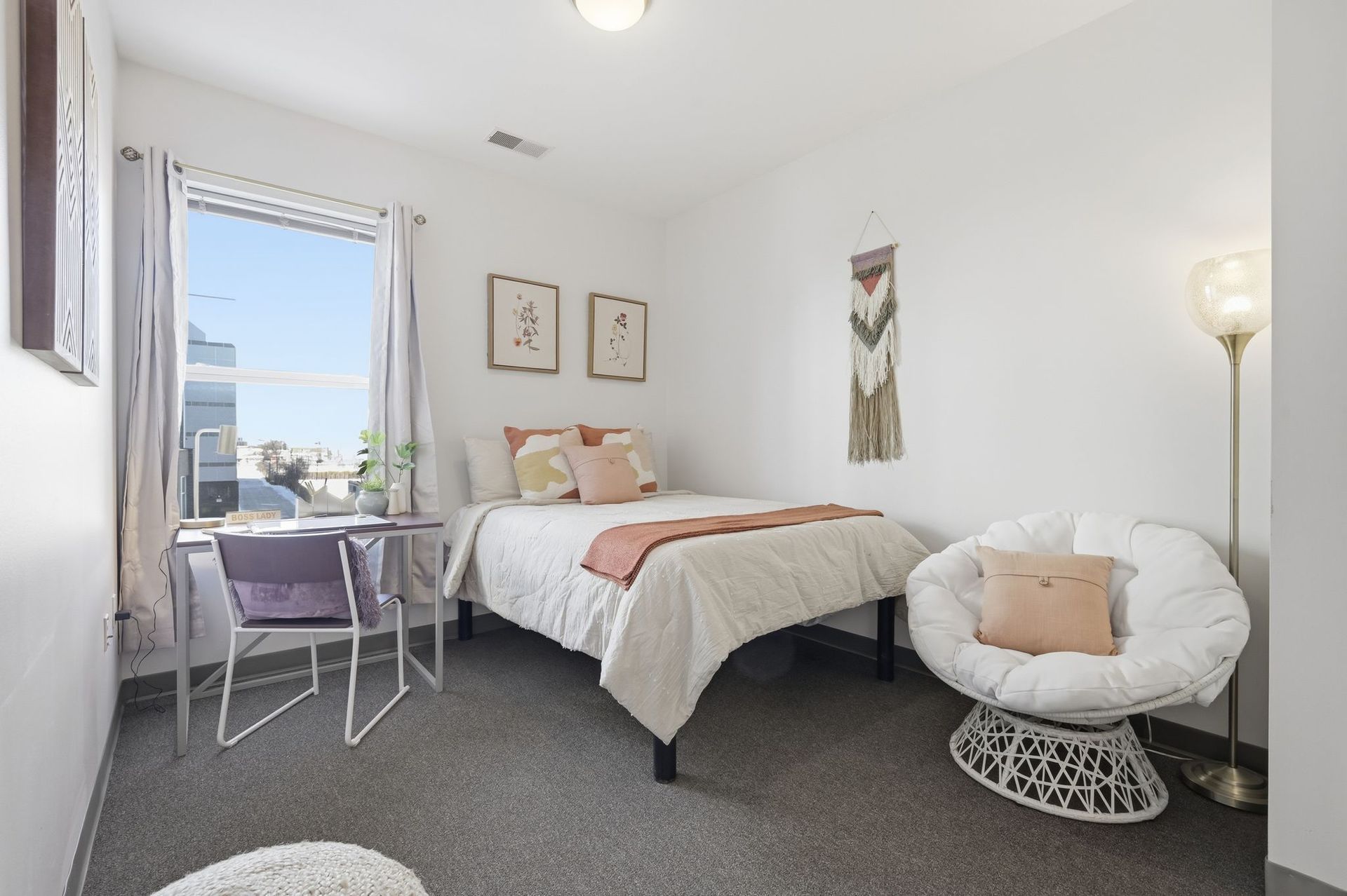 Bedroom with bed, desk, chair, window, decorations, and floor lamp.