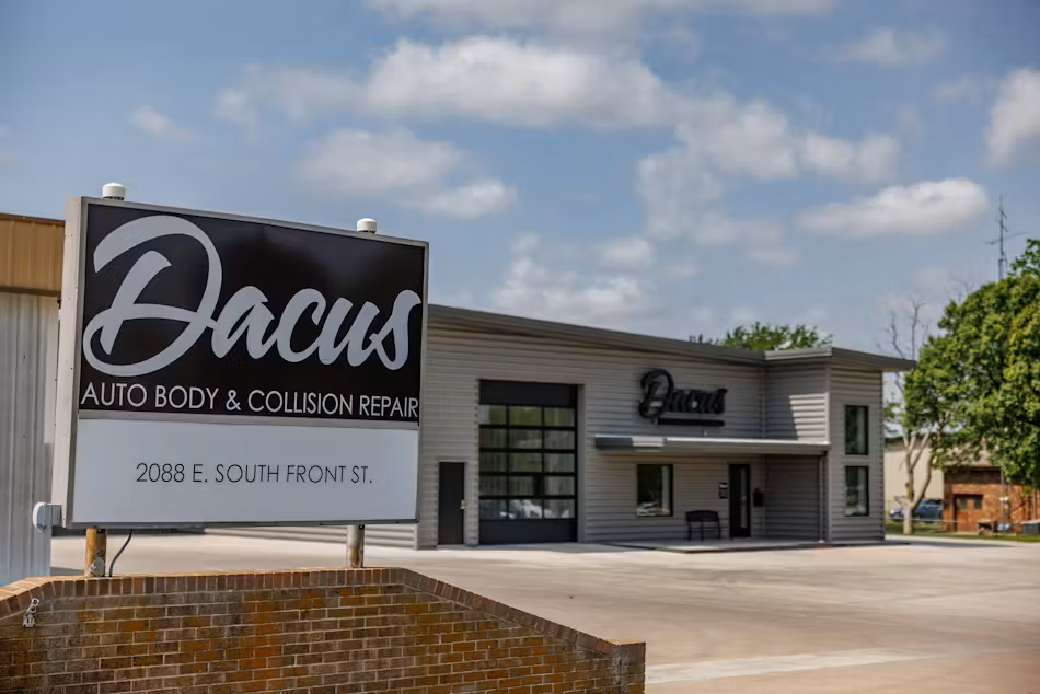 A man is polishing a blue car with a hand sander.