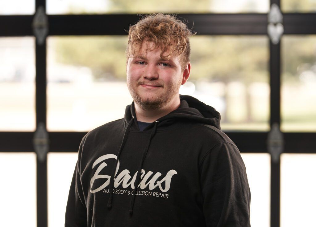 A young man wearing a black hoodie is smiling for the camera.
