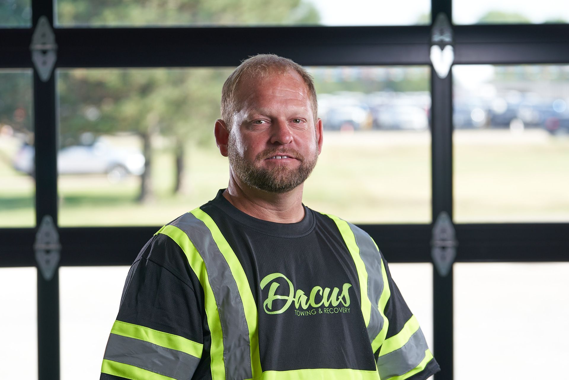 A man wearing a safety vest is standing in front of a garage door.