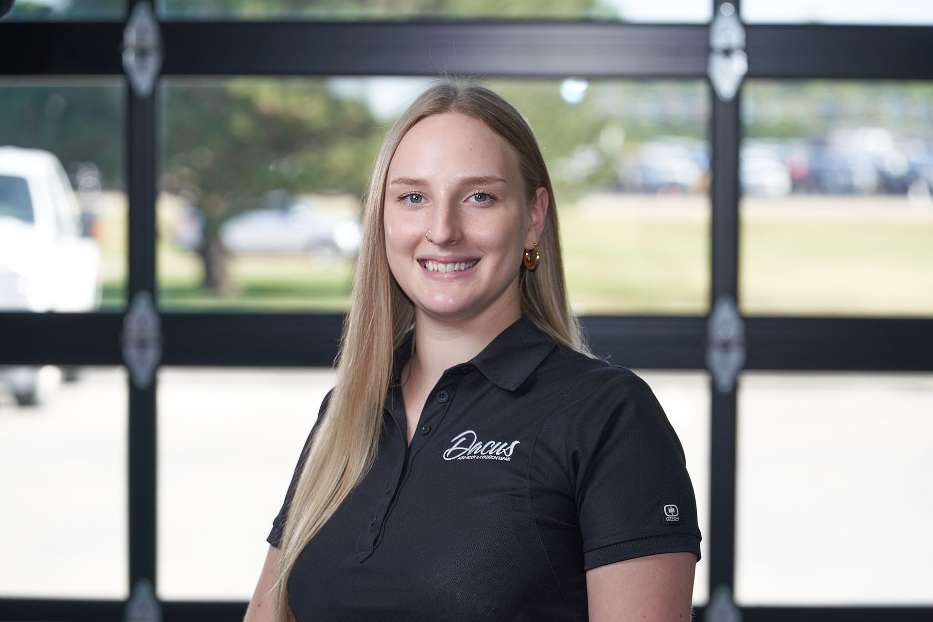 A woman in a black shirt is smiling in front of a garage door.