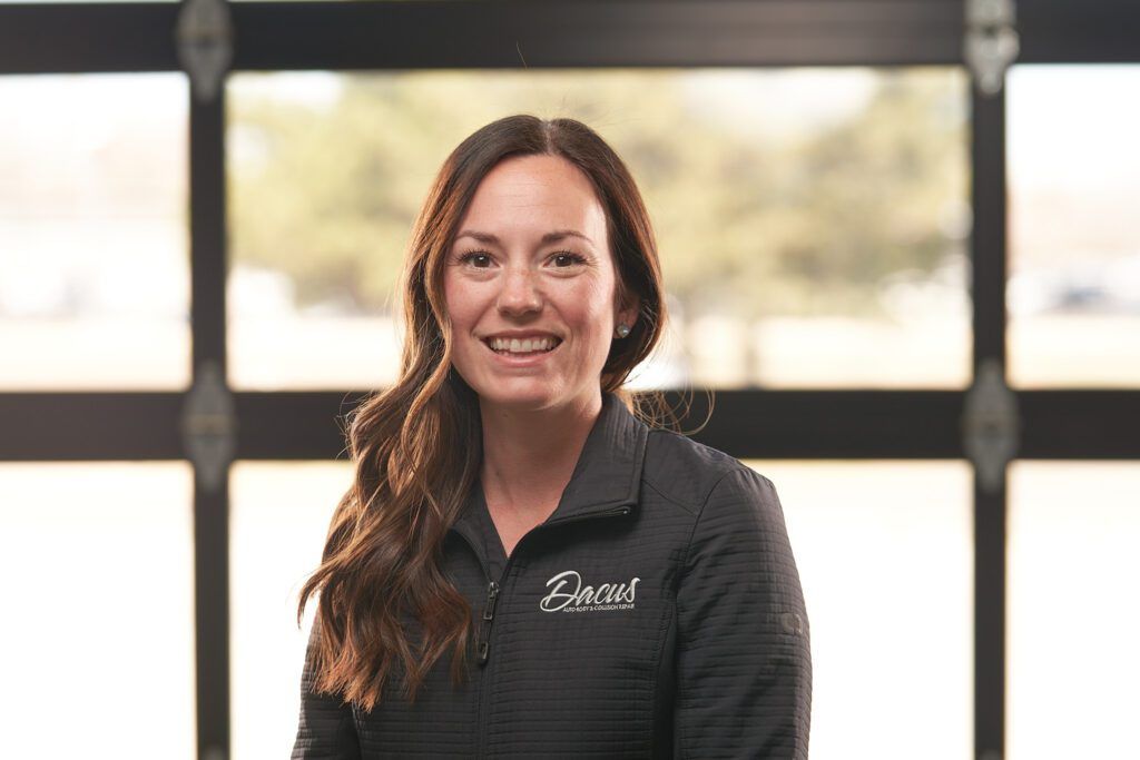 A woman in a black shirt is smiling in front of a garage door.