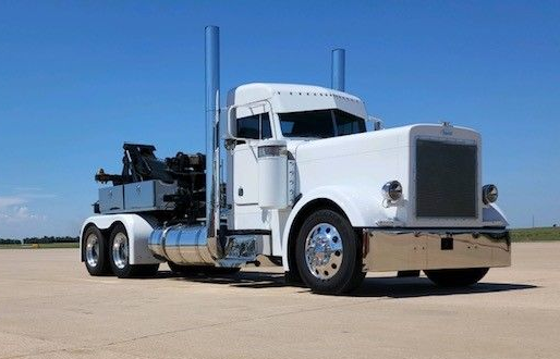 White semi-truck with chrome accents on a flat, blue-sky day.