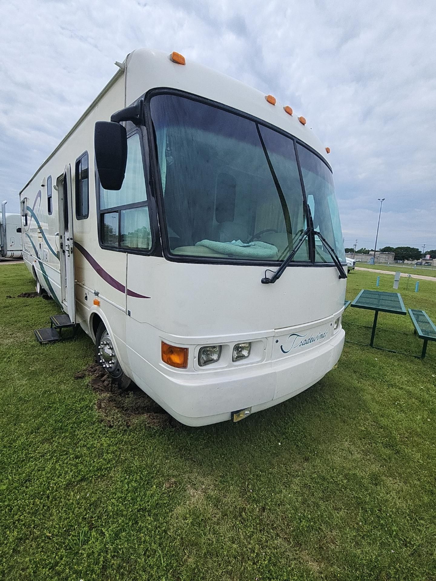 White RV parked on grass, overcast sky background.