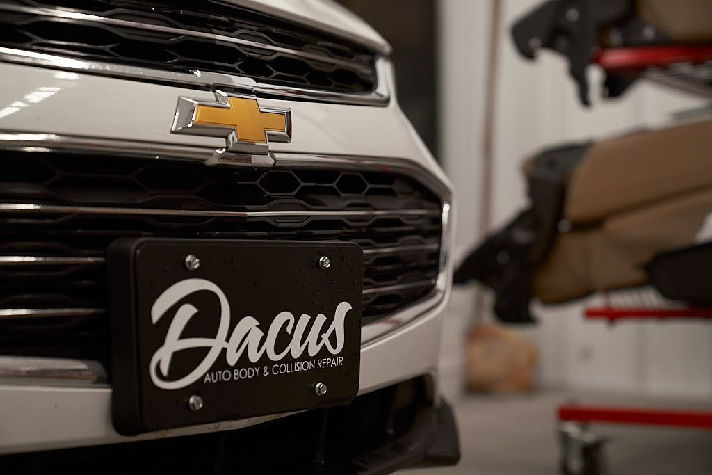 A white chevrolet with a black license plate is parked in a garage.