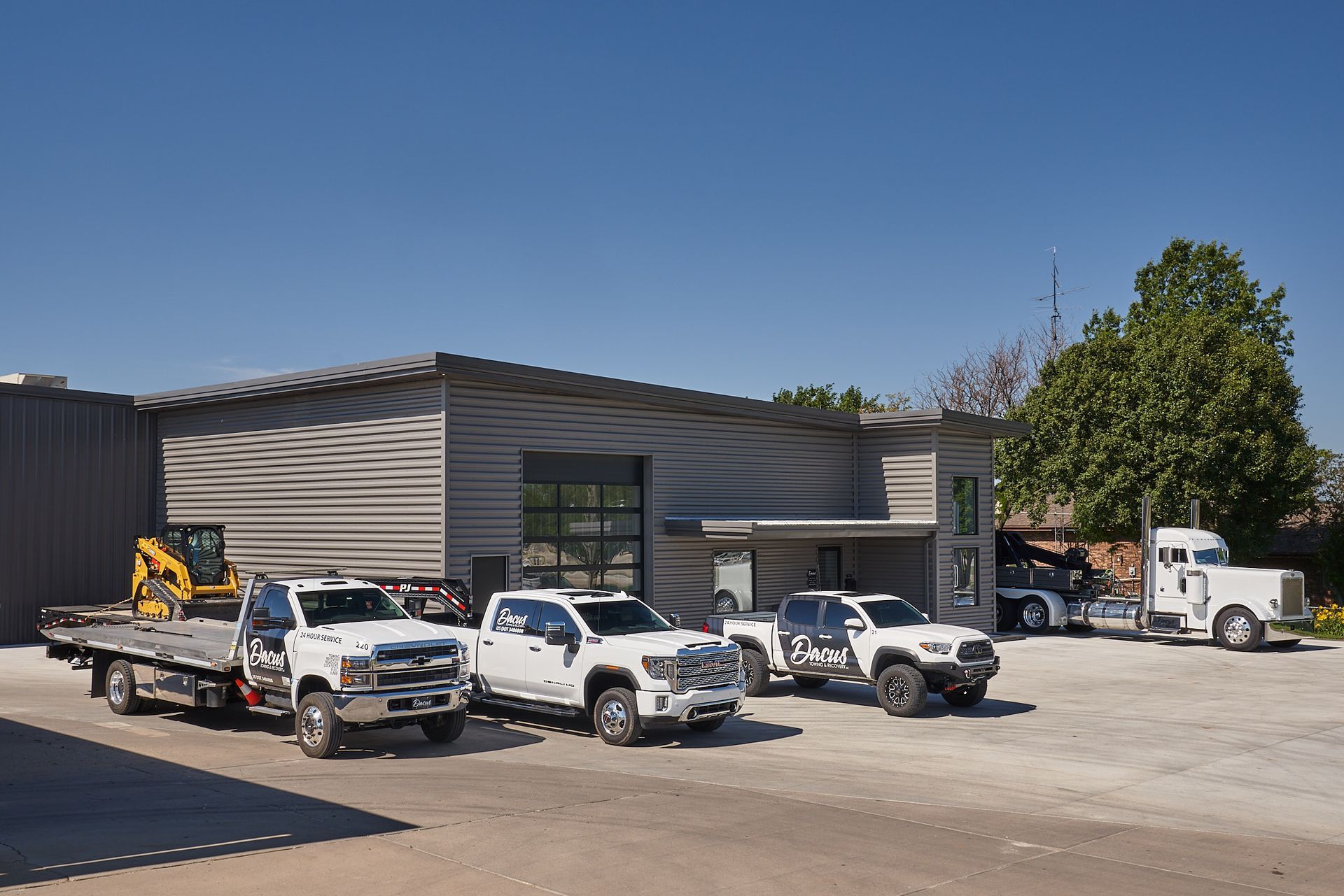 A row of tow trucks are parked in front of a building.