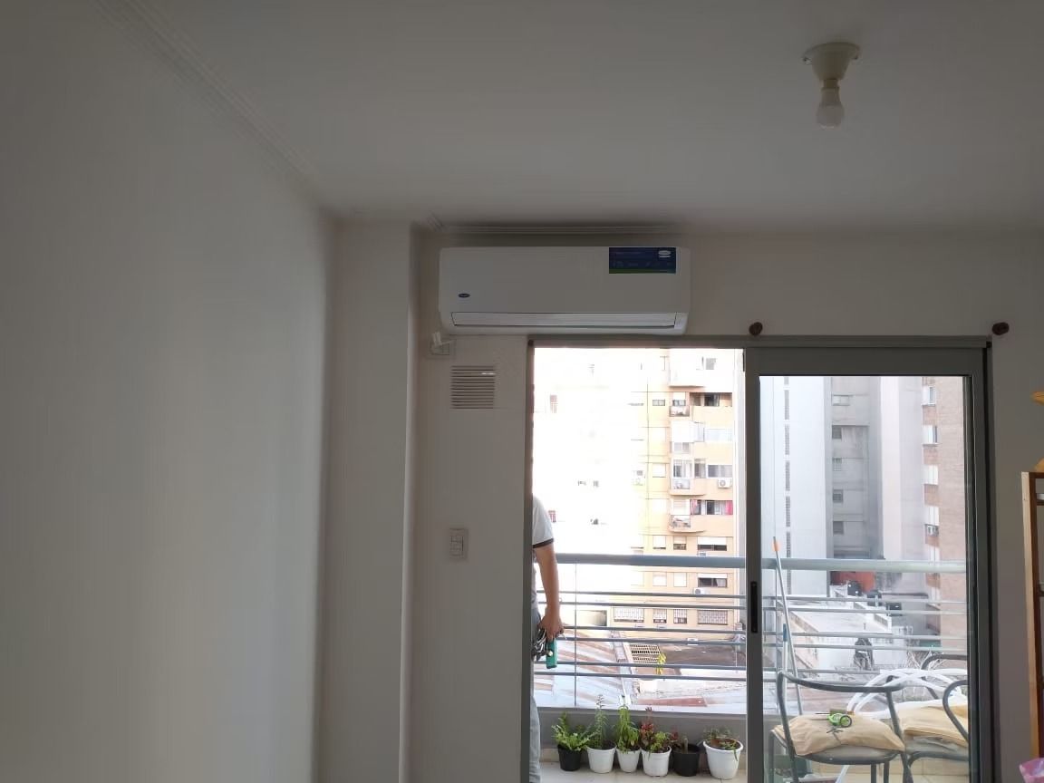 Aire acondicionado sobre una puerta corrediza de vidrio, con vista a un balcón con vista a la ciudad.