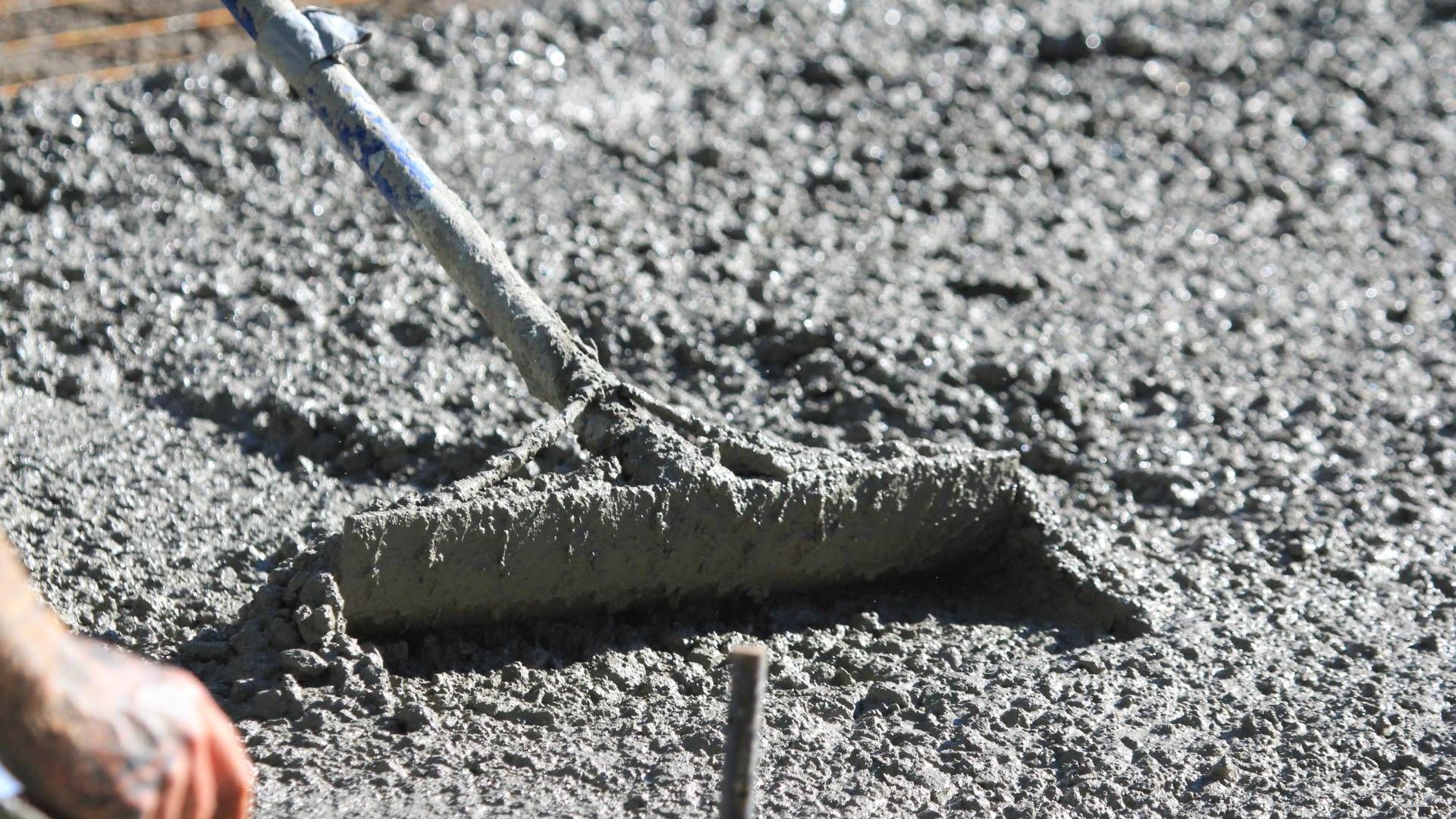 A person is spreading concrete with a rake.