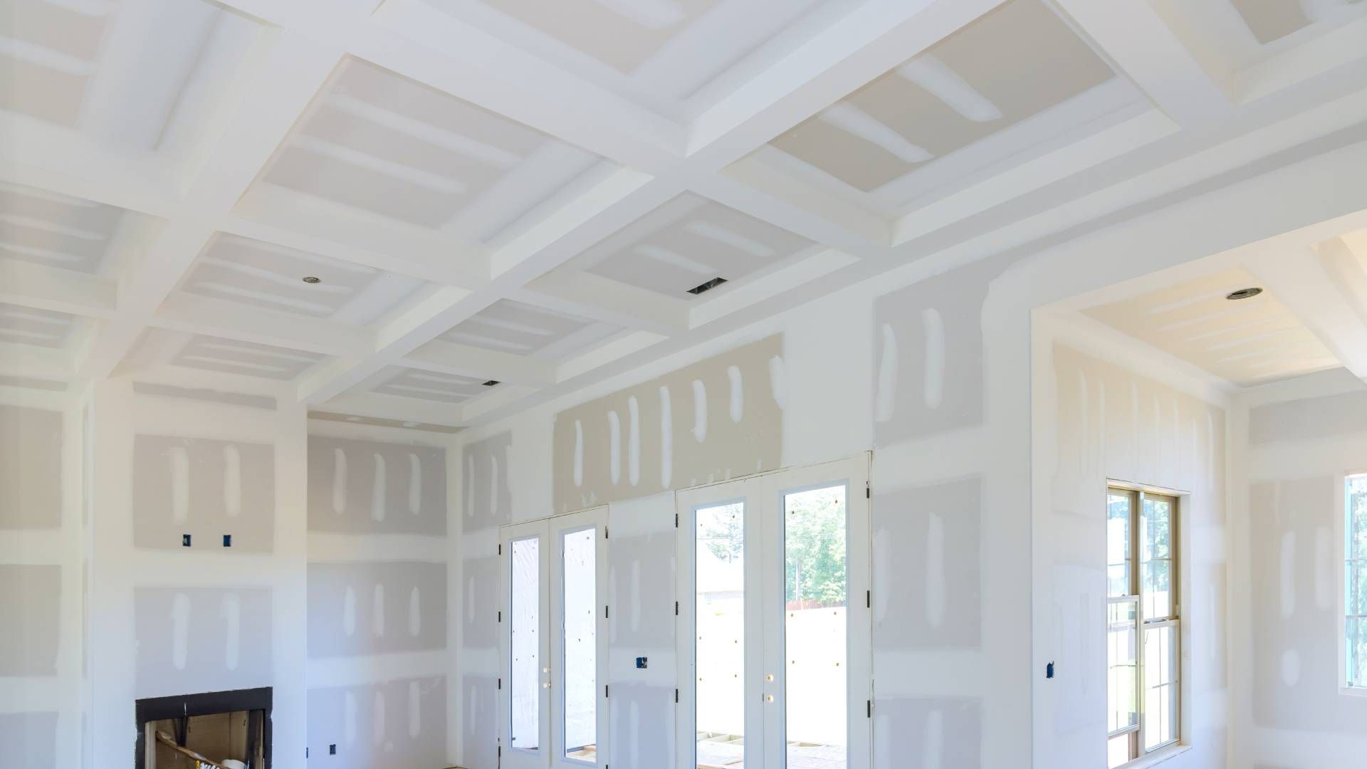 A living room in a house under construction with a fireplace and lots of windows.