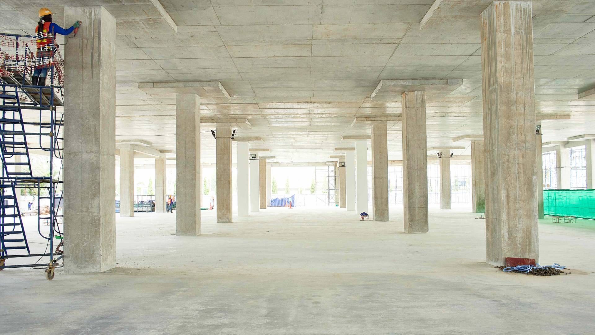 A man is standing on a scaffolding in an empty building under construction.