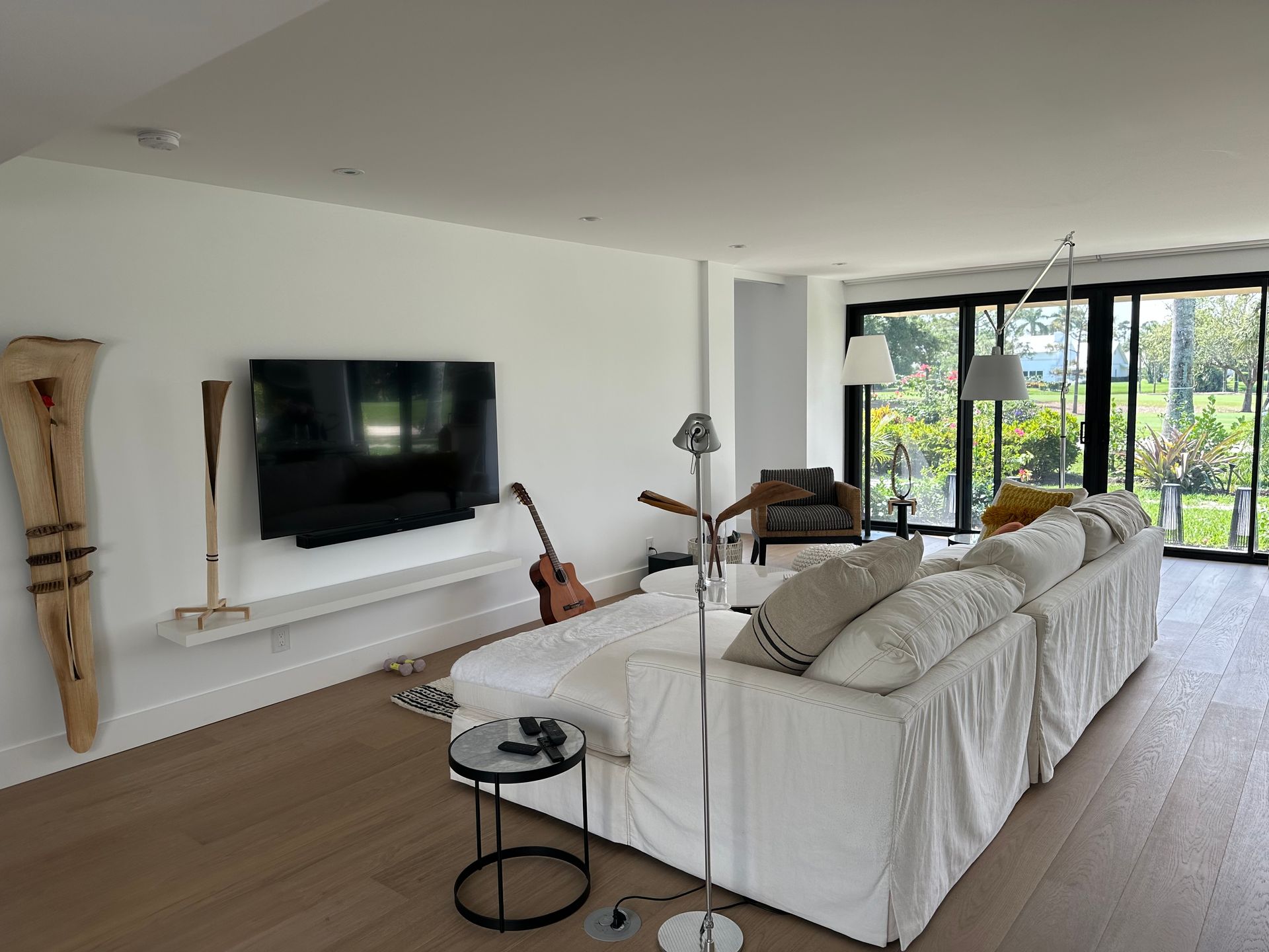 A living room with a large white couch and a flat screen tv on the wall.