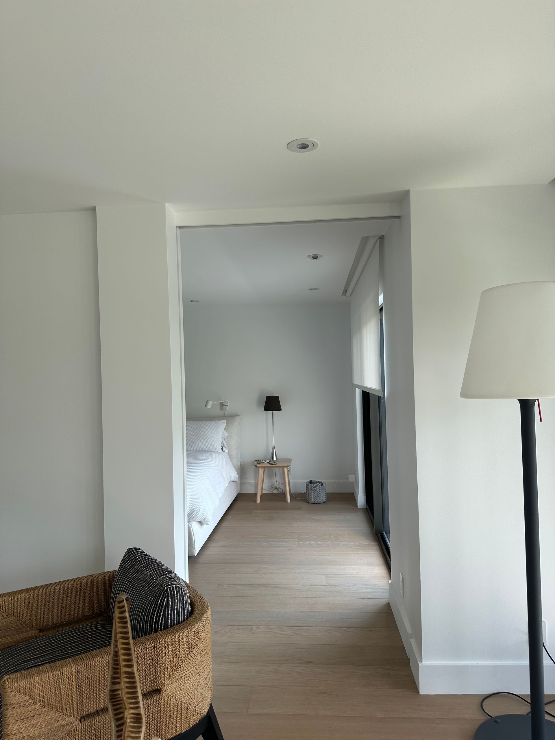 A living room with a lamp and a bed in the background