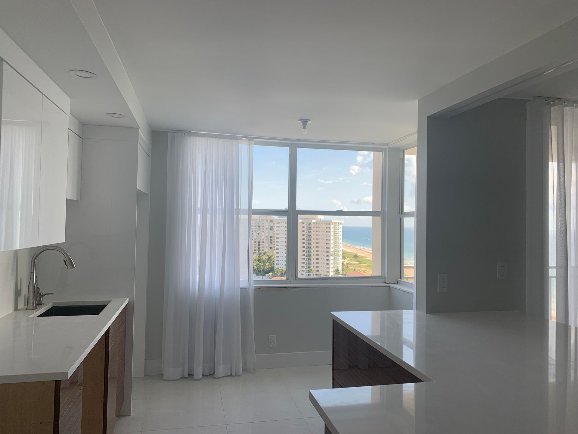 A kitchen with white cabinets and a large window