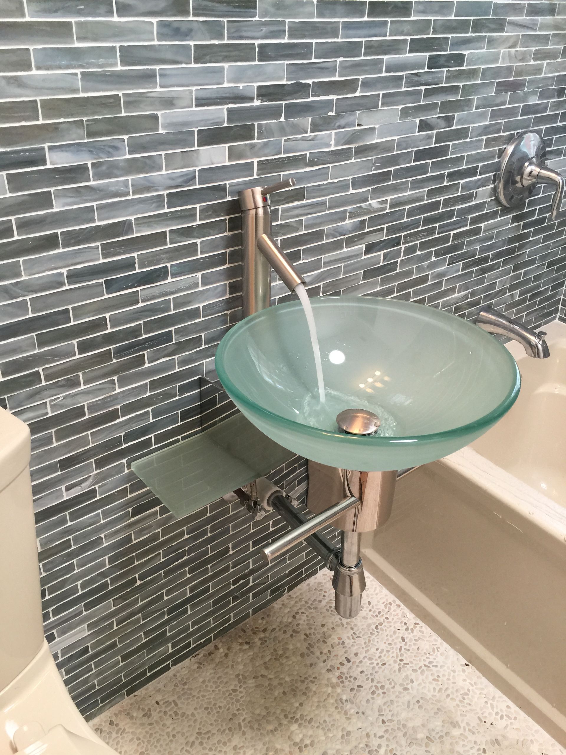 A bathroom with a glass sink and a toilet