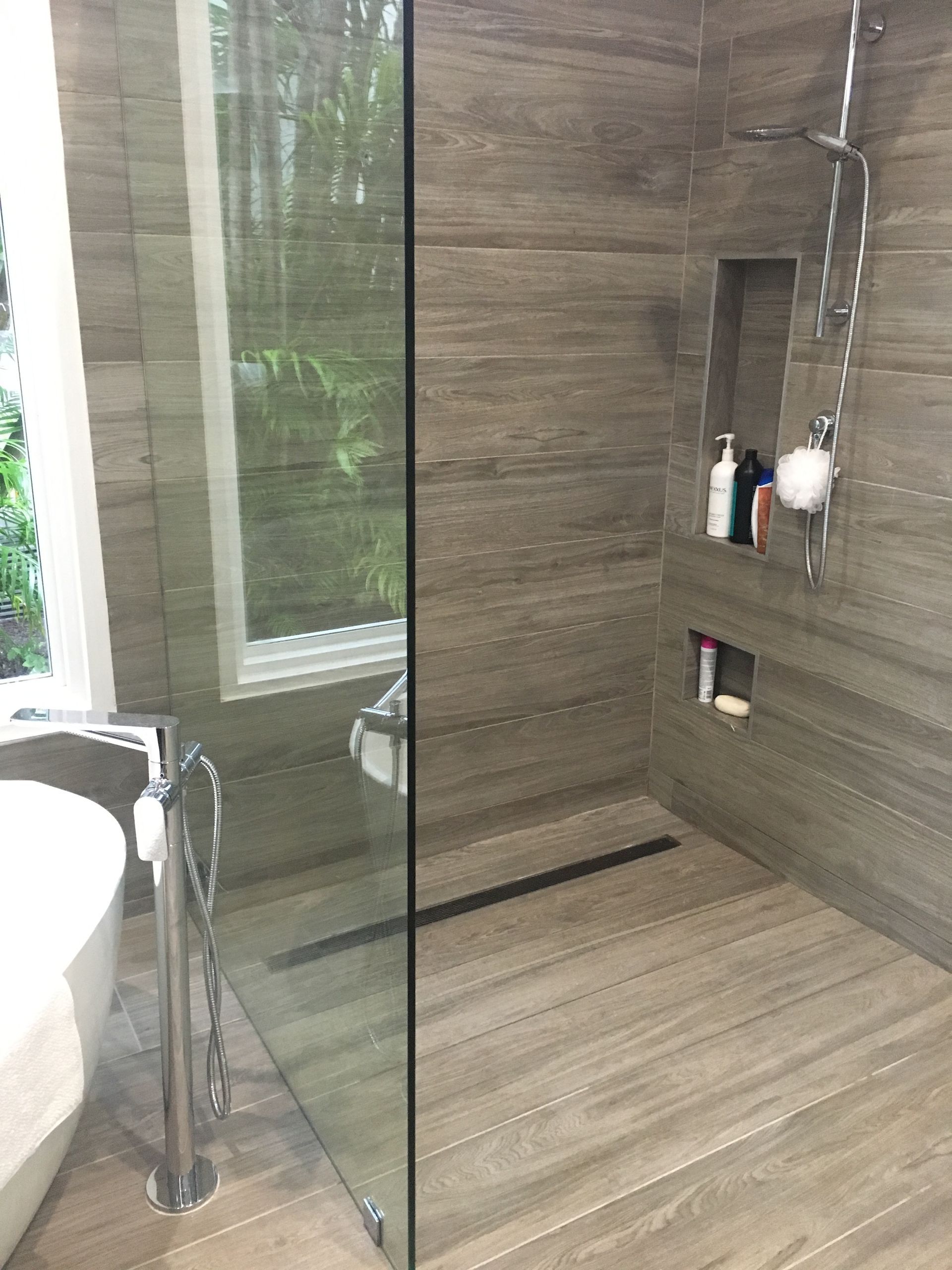 A bathroom with a walk in shower , sink , and window.