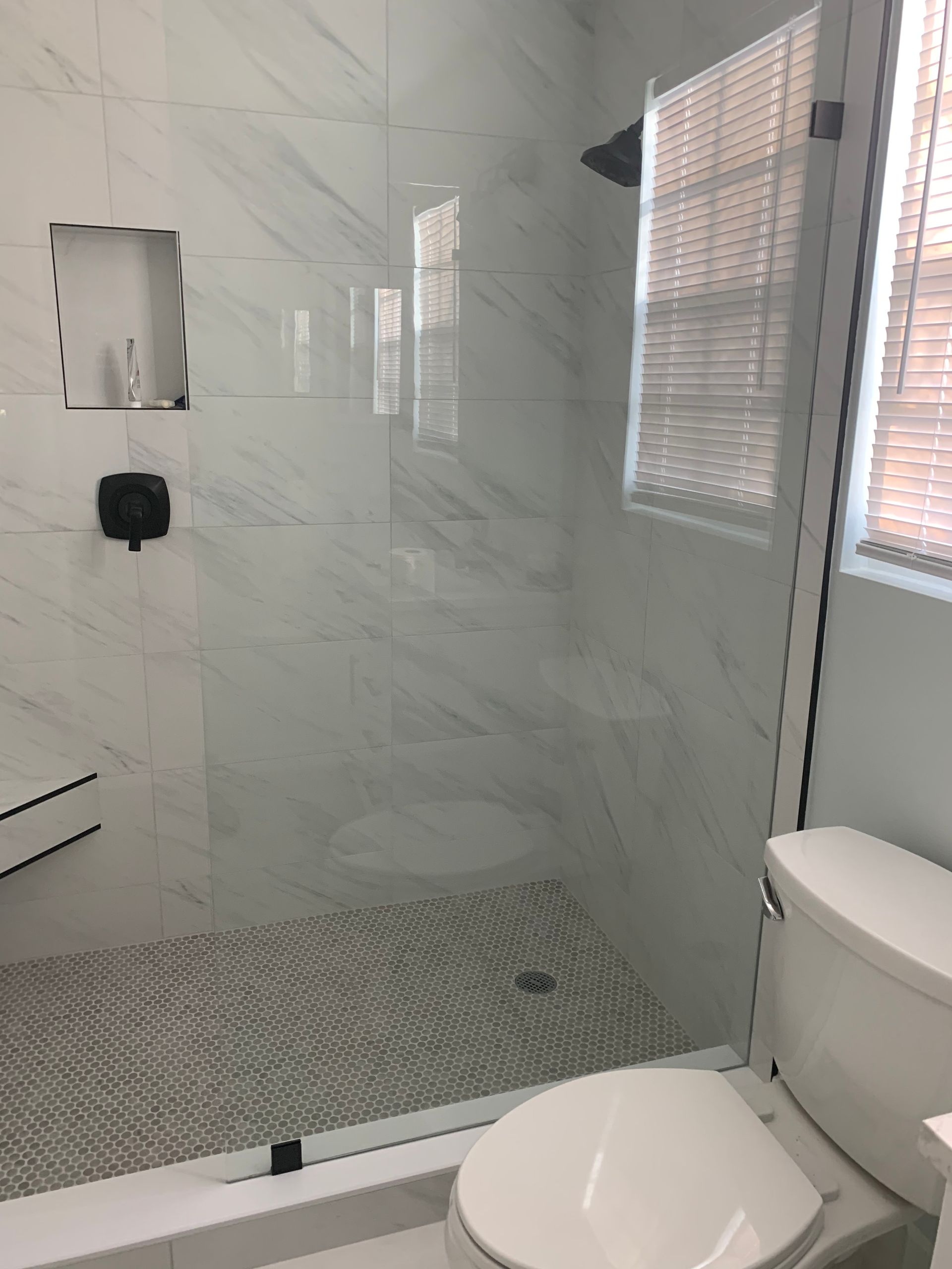 A bathroom with a toilet and a shower with a glass door.