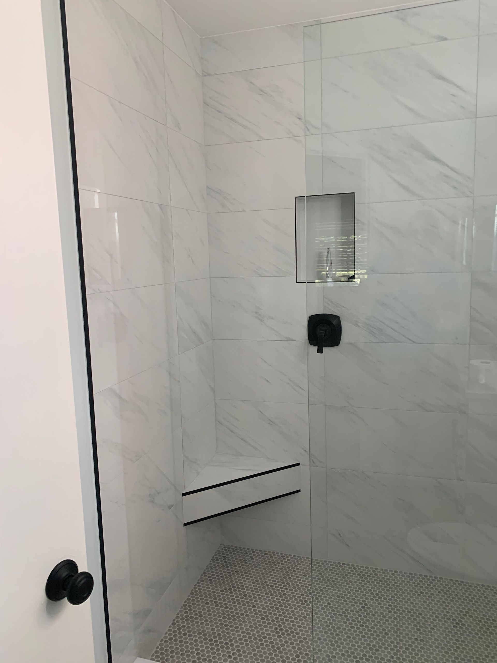 A bathroom with a walk in shower with a glass door.