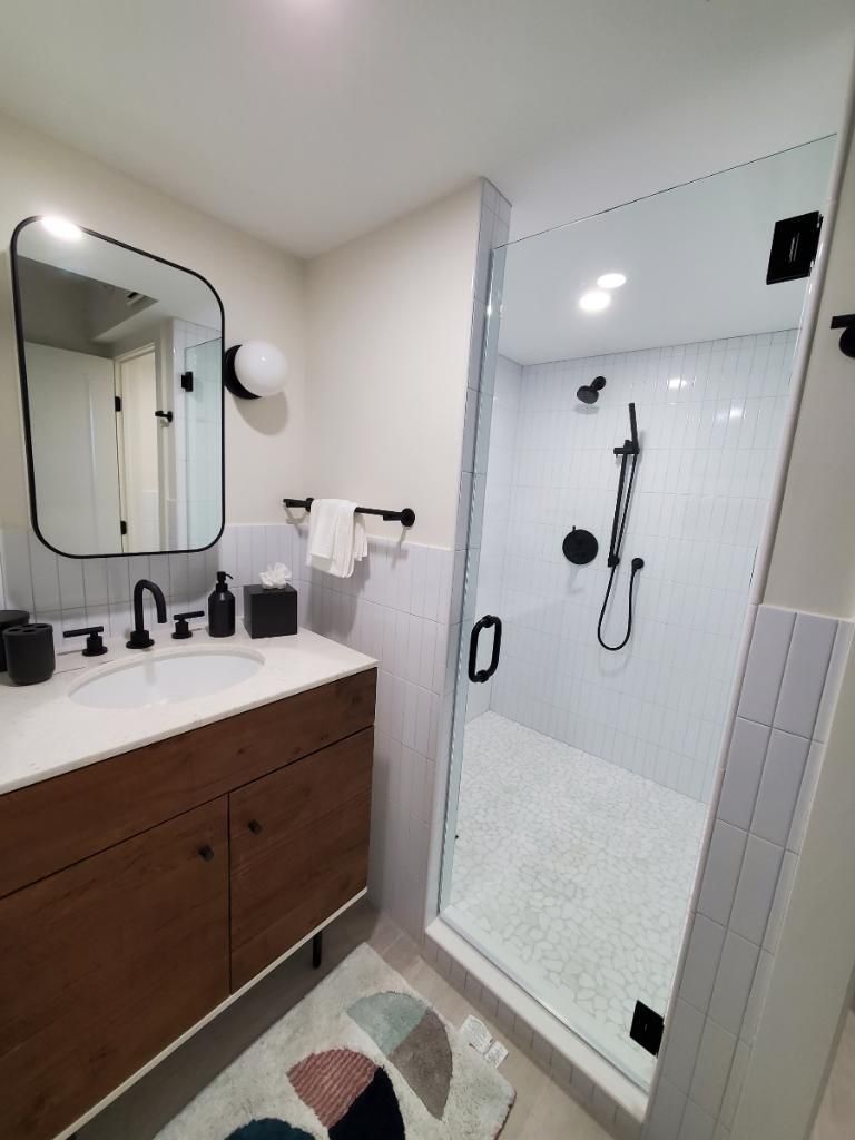 A bathroom with a sink , mirror , and walk in shower.