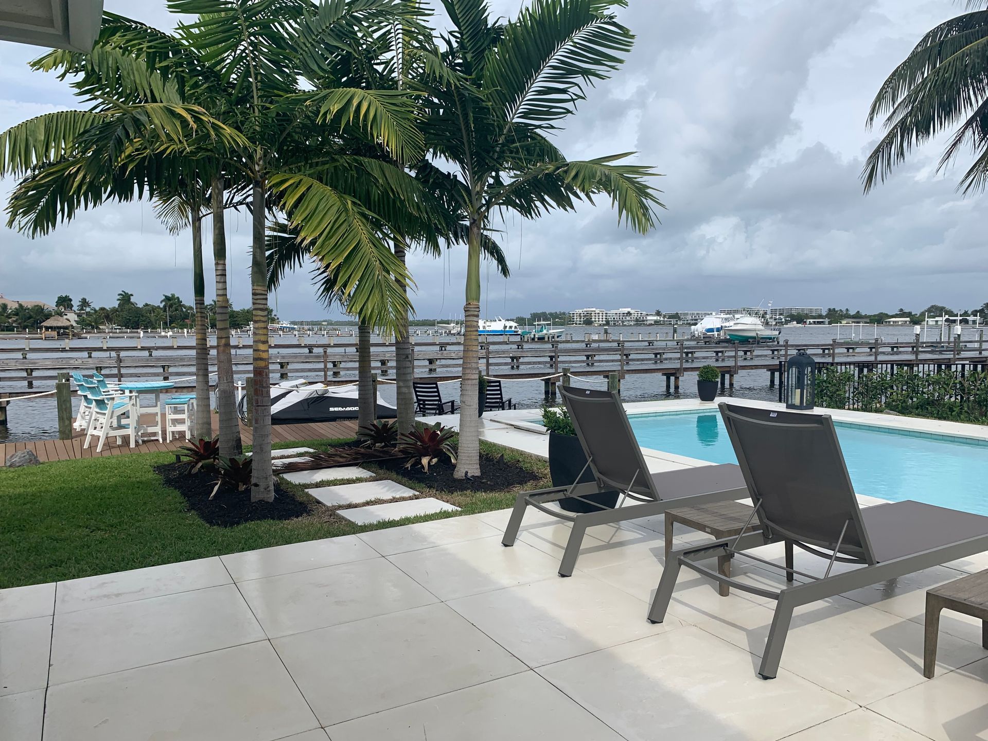 A swimming pool with chairs and a dock in the background