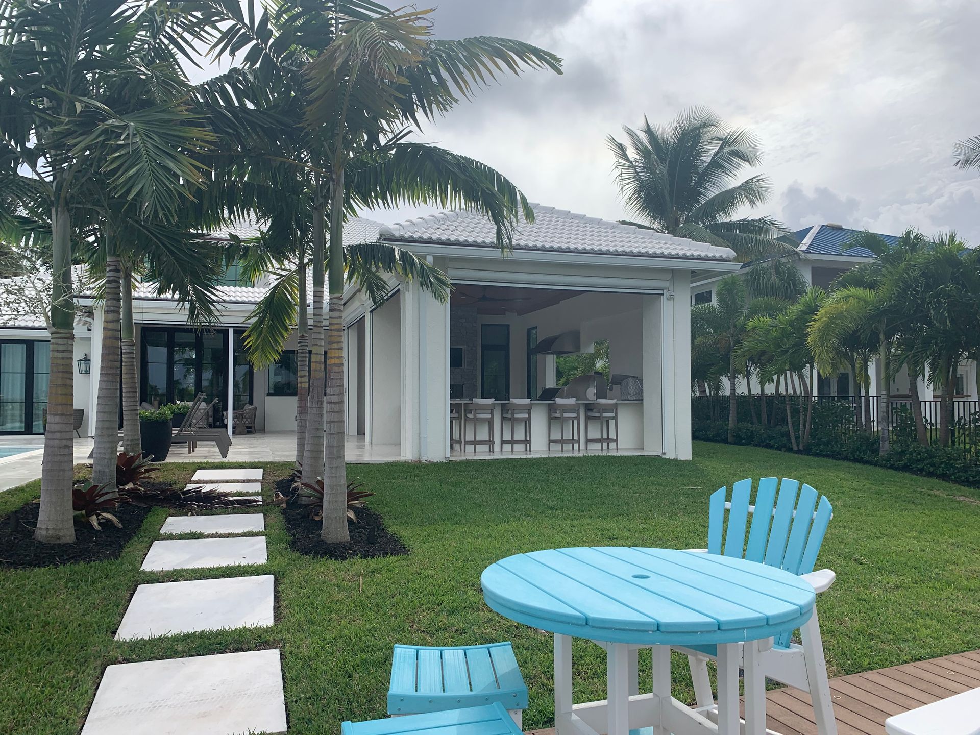 A white house with a blue table and chairs in front of it