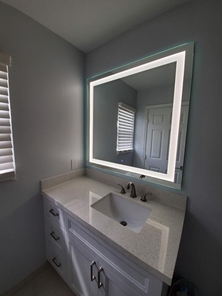 A bathroom with a sink and a large mirror.