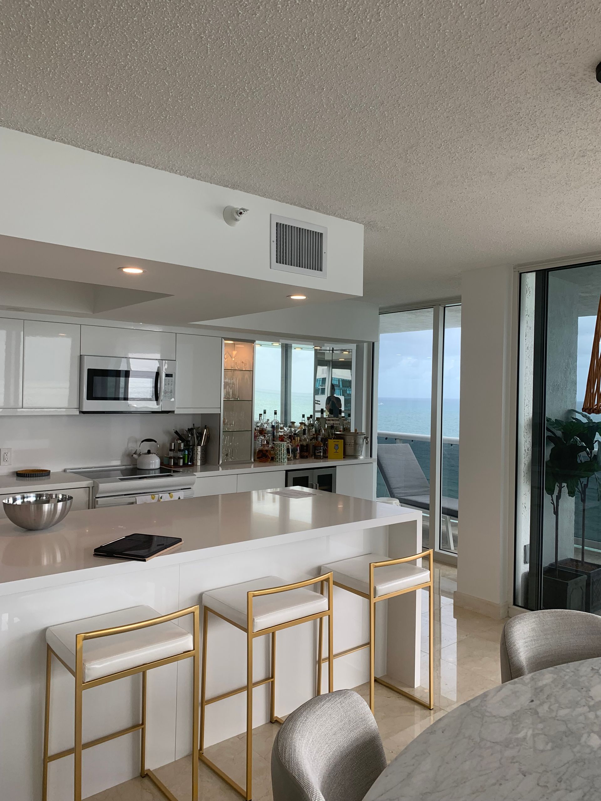 A kitchen with white cabinets and gold stools