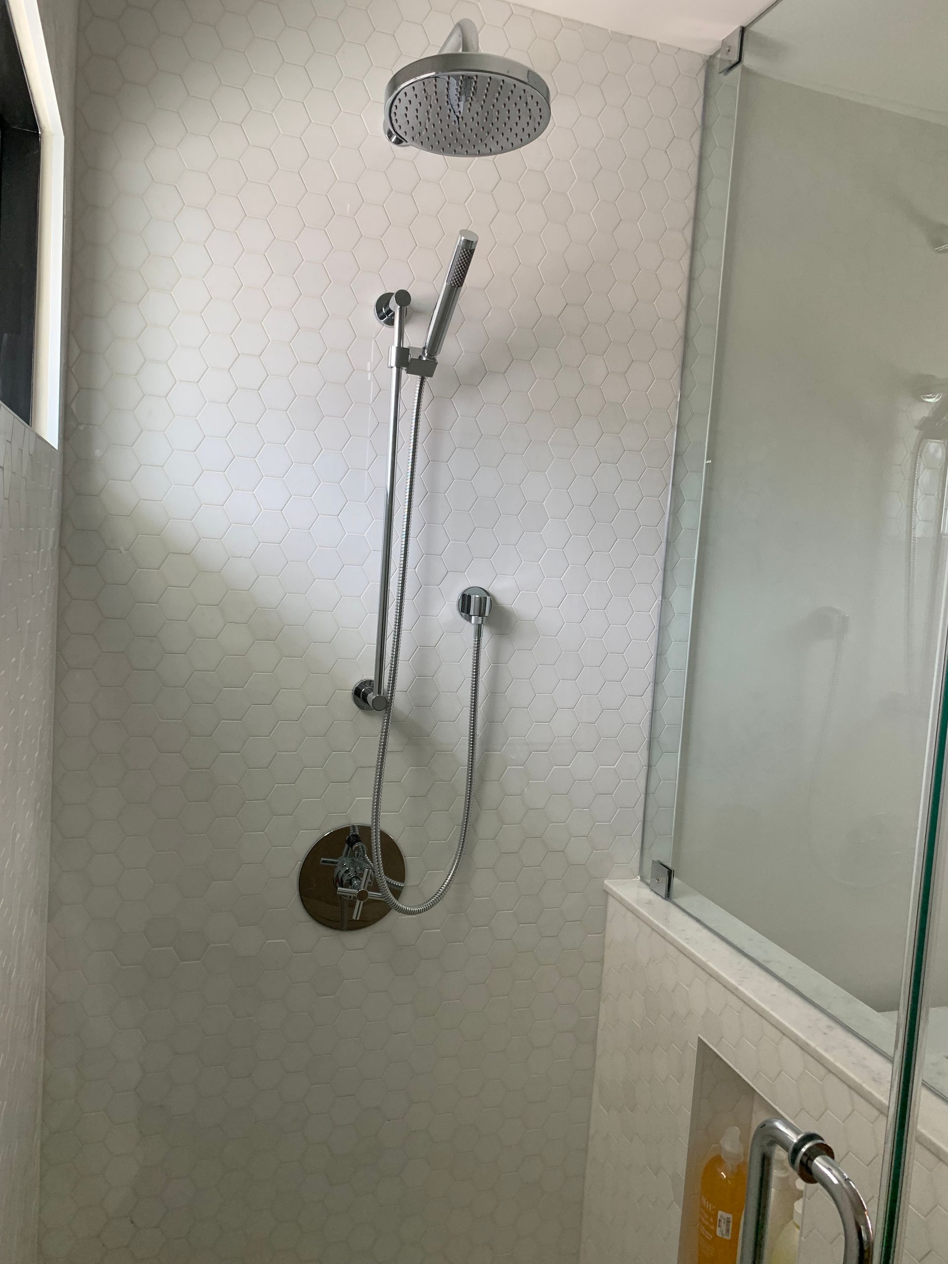A shower head is hanging from the ceiling in a bathroom.