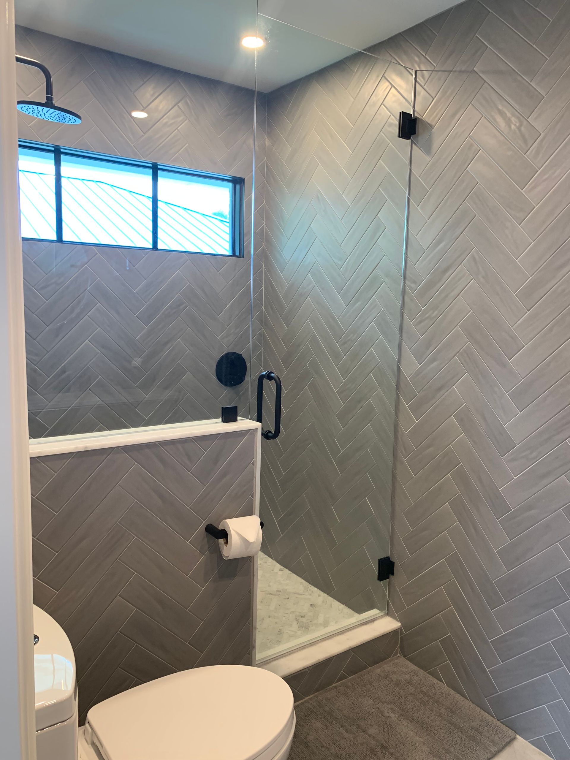 A bathroom with a toilet , shower and mirror.