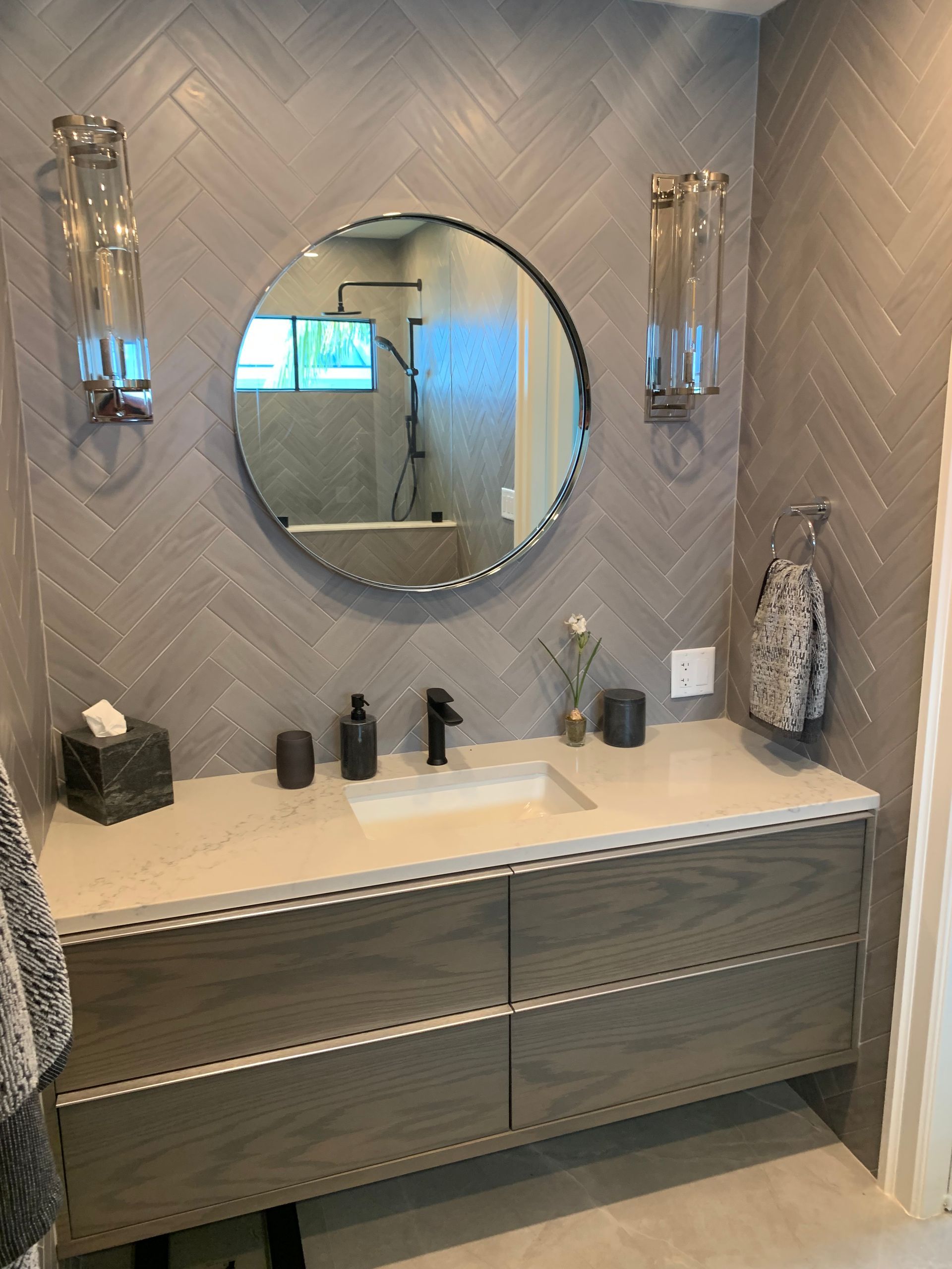 A bathroom with a sink and a round mirror.