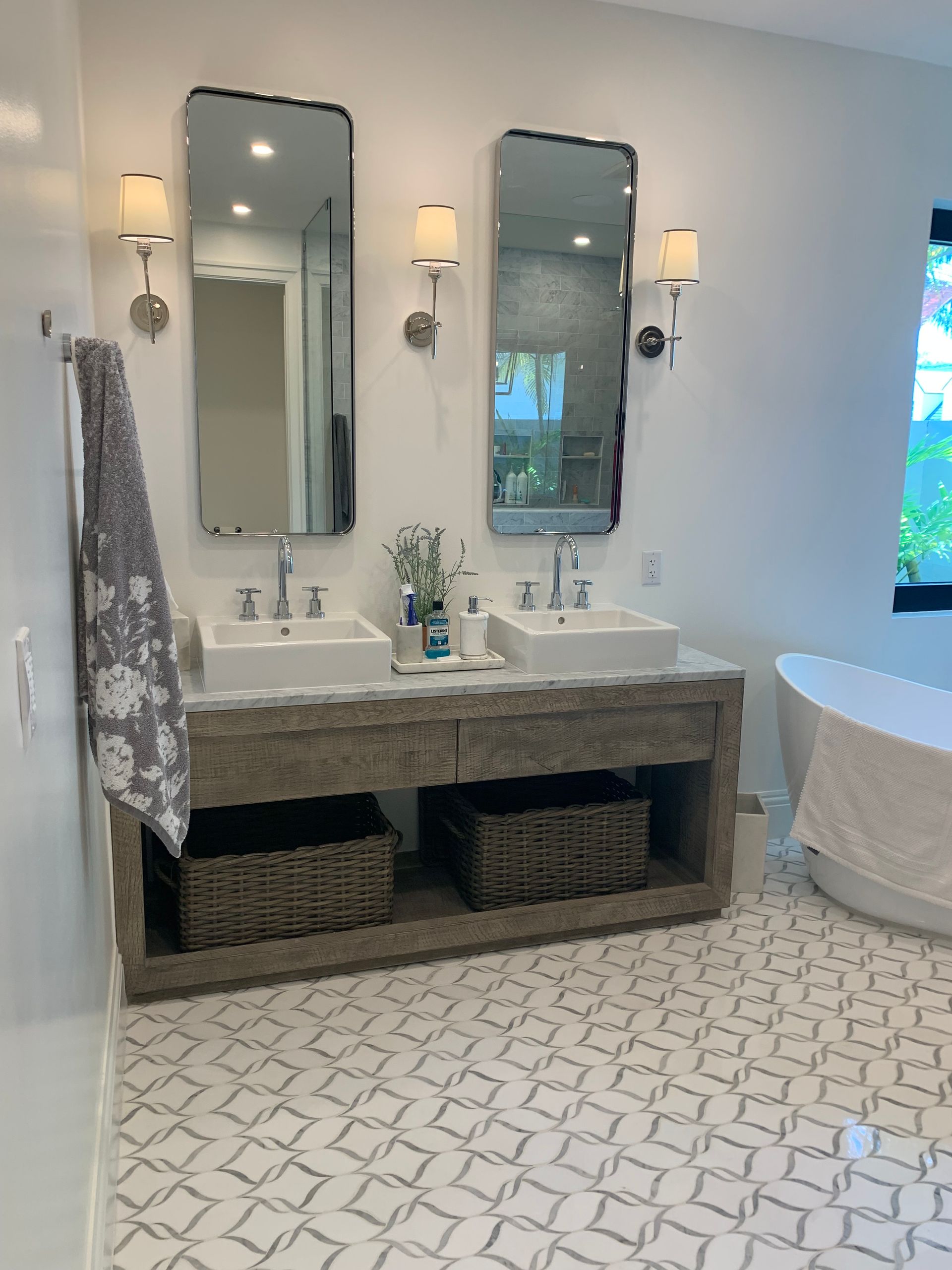 A bathroom with two sinks , two mirrors and a tub.