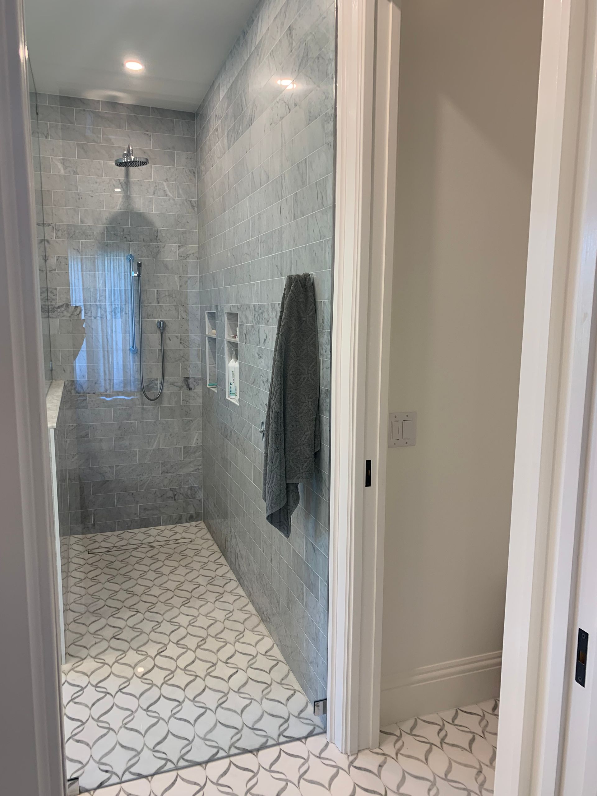 A bathroom with a walk in shower and a towel hanging on the wall.