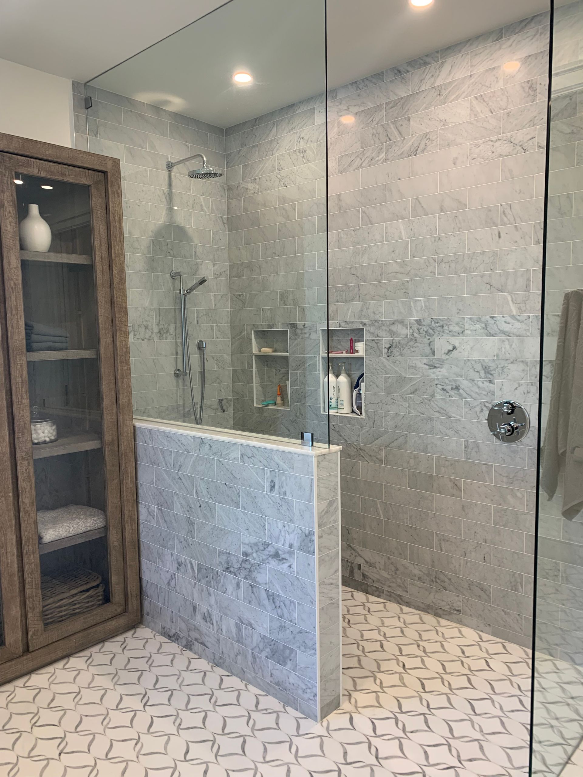 A bathroom with a walk in shower and a glass door.